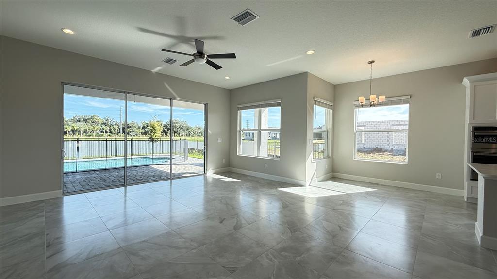 A bright living area features large tile floors, a ceiling fan, and sliding glass patio doors — 32523 NEROLI STREET, WESLEY CHAPEL, FL