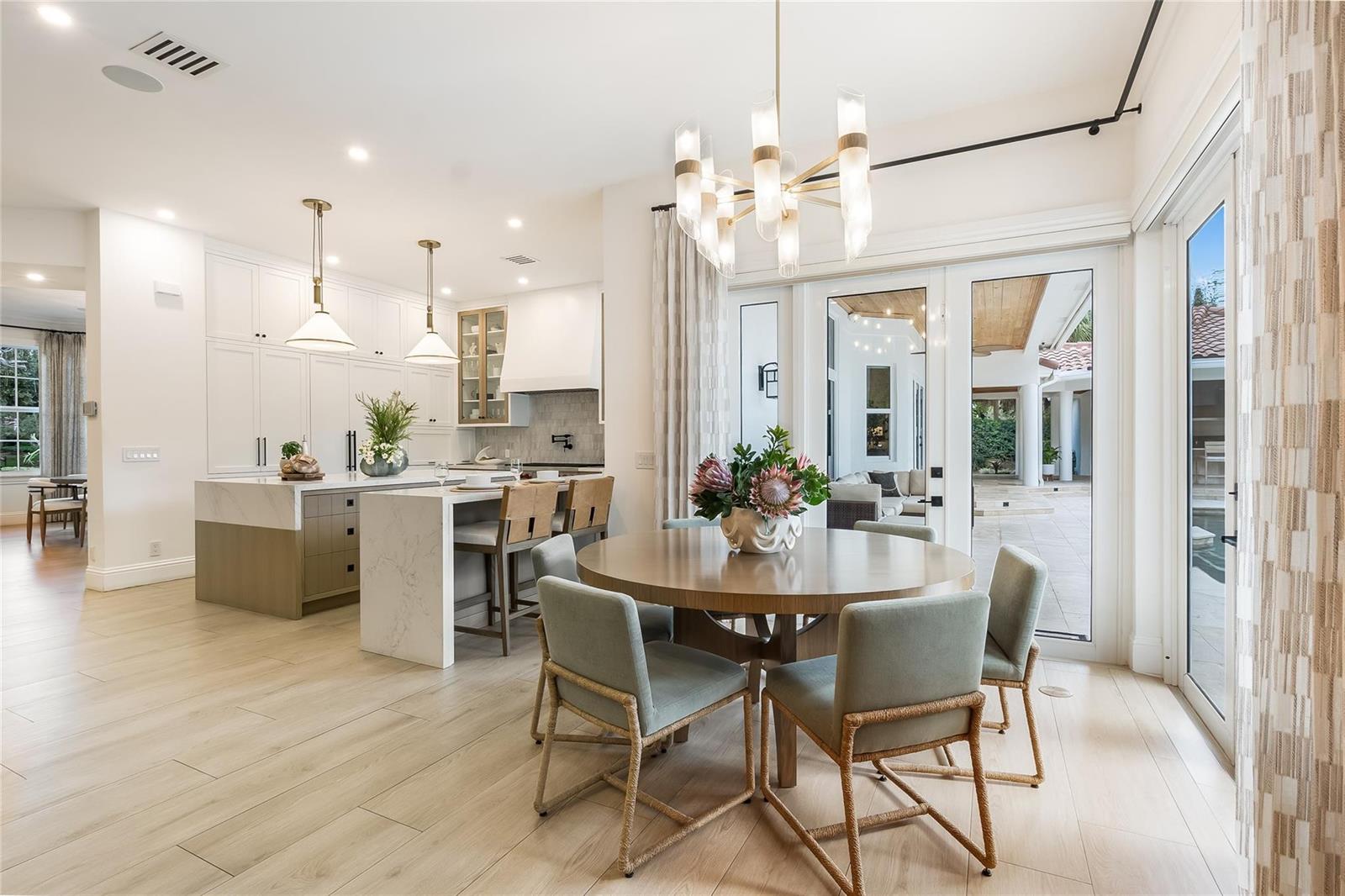 A bright kitchen and dining area with a round table, island, and glass patio doors — 2825 Hackney Road, Weston FL 33331, WESTON, FL