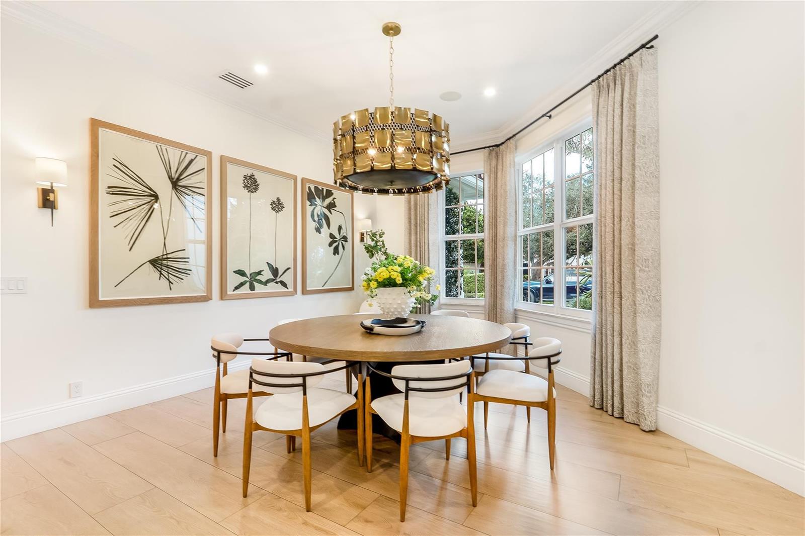 A dining room features a round wooden table, white chairs, and a gold drum chandelier — 2825 Hackney Road, Weston FL 33331, WESTON, FL