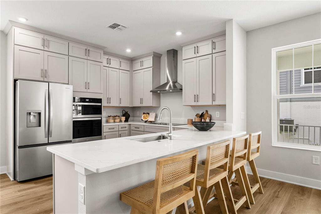 A modern kitchen features light gray cabinets, stainless steel appliances, and a white quartz island — 320 43RD AVENUE N, ST PETERSBURG, FL