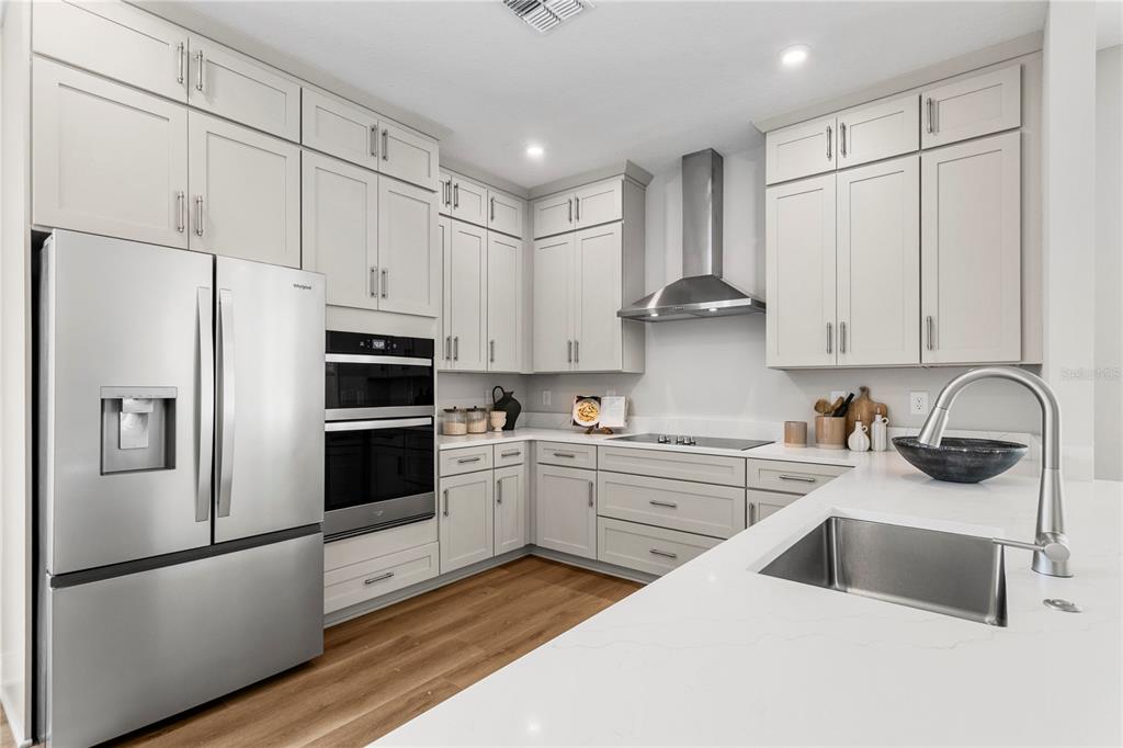 A modern kitchen features light gray cabinets, stainless steel appliances, and a white quartz countertop — 320 43RD AVENUE N, ST PETERSBURG, FL