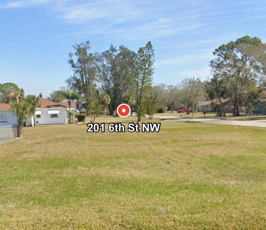 A vacant, grassy residential lot is shown under a clear blue sky — 201 6TH STREET NW, RUSKIN, FL