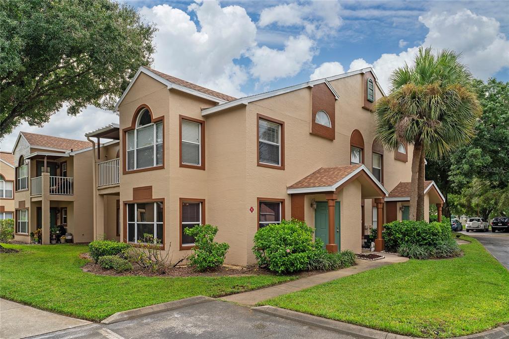 A two-story tan stucco apartment building with brown trim, arched windows, and a palm tree — 5424 E MICHIGAN STREET UNIT 7, ORLANDO, FL