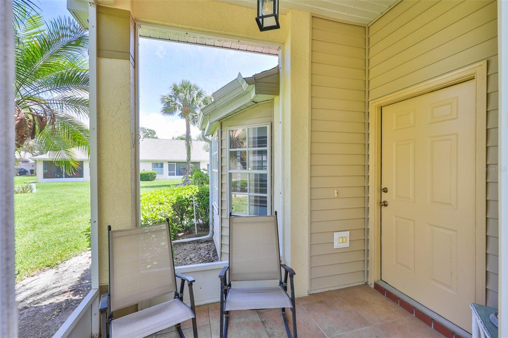 A screened-in porch with two chairs, tile flooring, and a door leading inside — 2429 NEW HAVEN CIRCLE, SUN CITY CENTER, FL