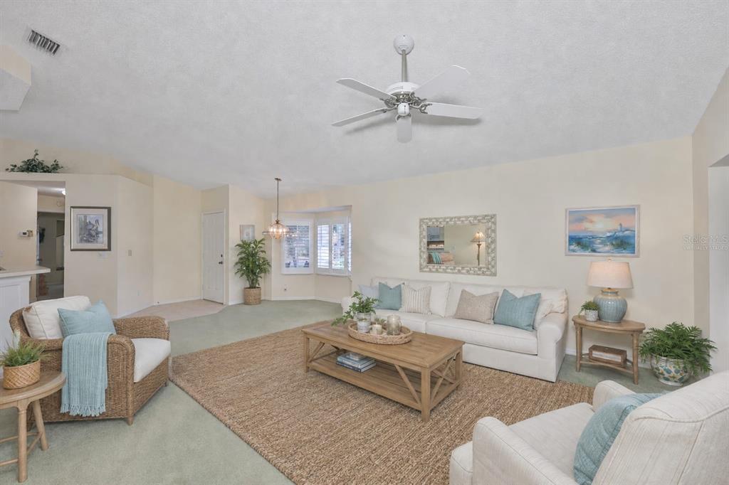 A living room features a white sofa, wicker armchair, wooden coffee table, and ceiling fan — 2429 NEW HAVEN CIRCLE, SUN CITY CENTER, FL