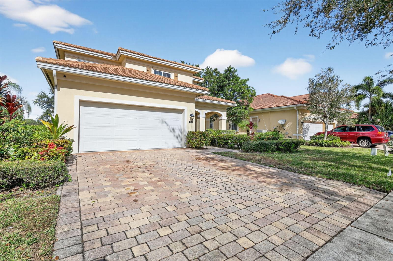 A two-story house with a white garage door and a paved driveway under a blue sky — 6720 Osage Circle, FL 33413, FL