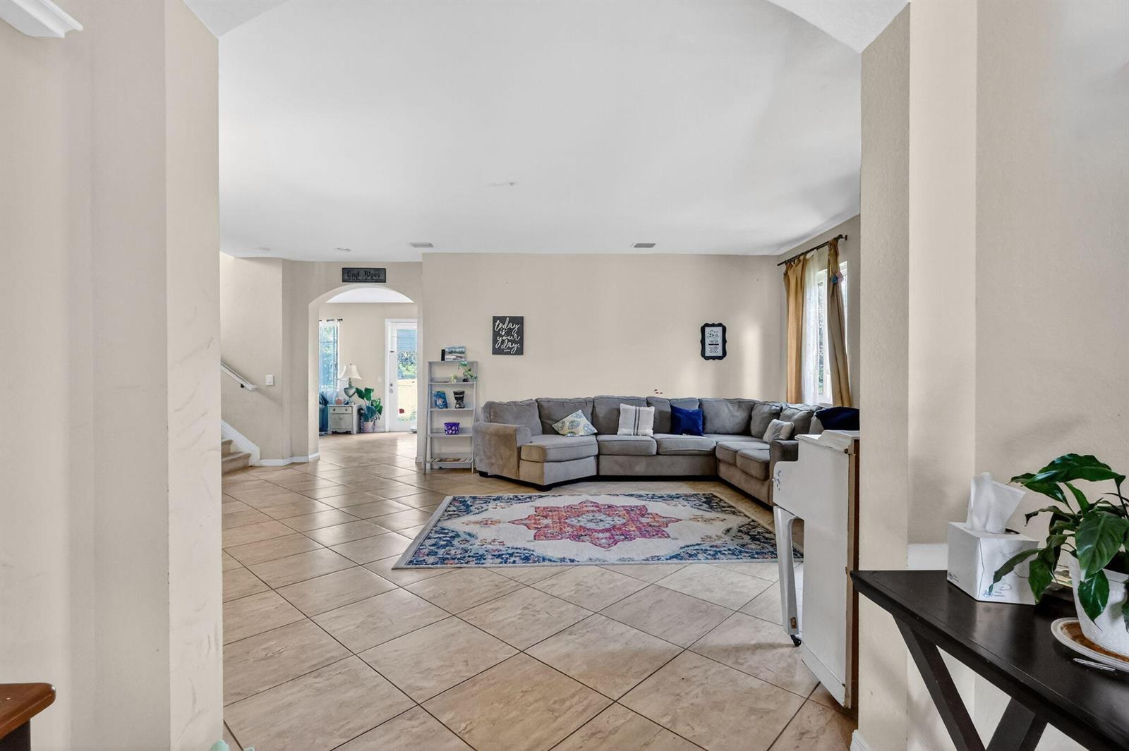 A living room features a large gray sectional sofa, a patterned rug, and tile flooring — 6720 Osage Circle, FL 33413, FL