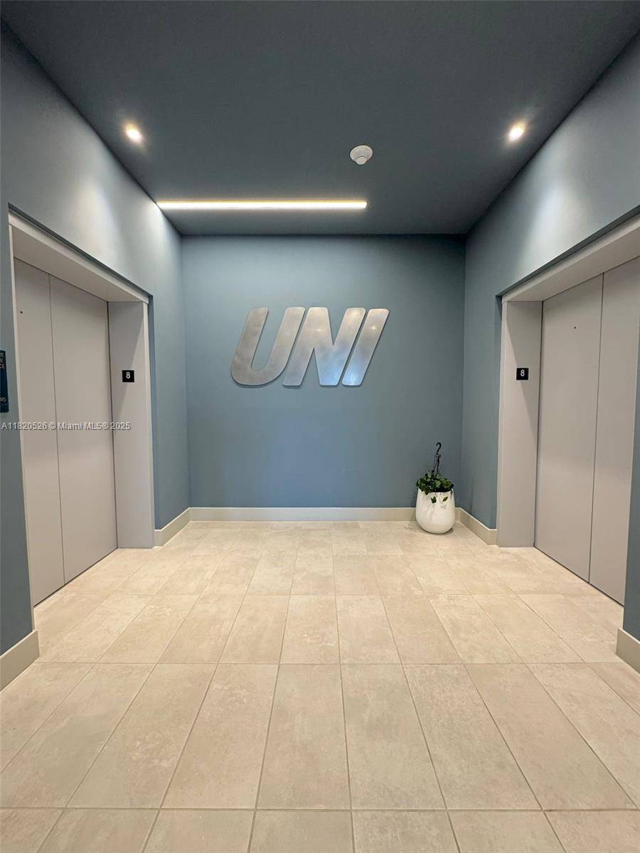 This elevator lobby features light tile flooring, blue walls, and a large metal UNI sign — 1642 NE 1st Ave # 2303, Miami FL 33132, MIAMI, FL