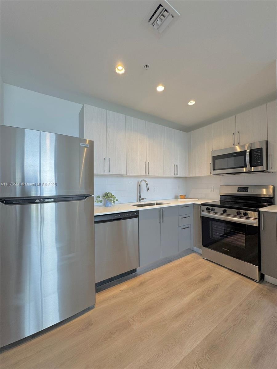 A modern kitchen features stainless steel appliances, light wood-grain cabinets, and light-colored countertops — 1642 NE 1st Ave # 2303, Miami FL 33132, MIAMI, FL