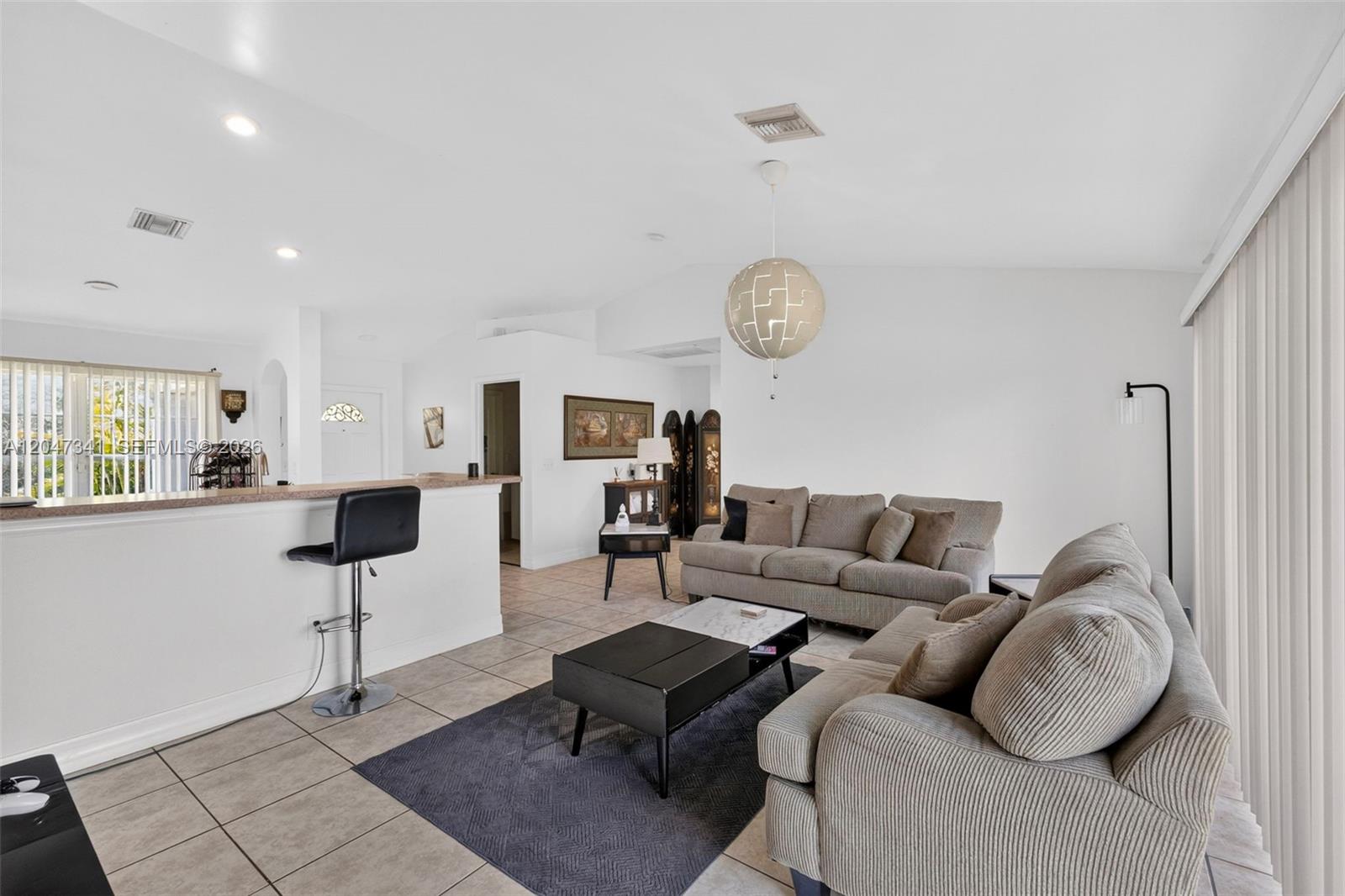 A living room features a beige sofa, a dark coffee table, and a breakfast bar — 2501 57th Street West, Lehigh Acres FL 33971, LEHIGH ACRES, FL