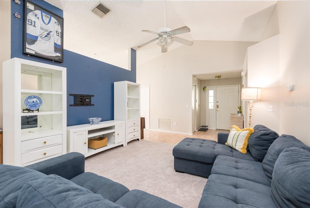 A living room features a blue accent wall, white shelving, and a blue sectional sofa — 5917 TAYWOOD DRIVE, TAMPA, FL