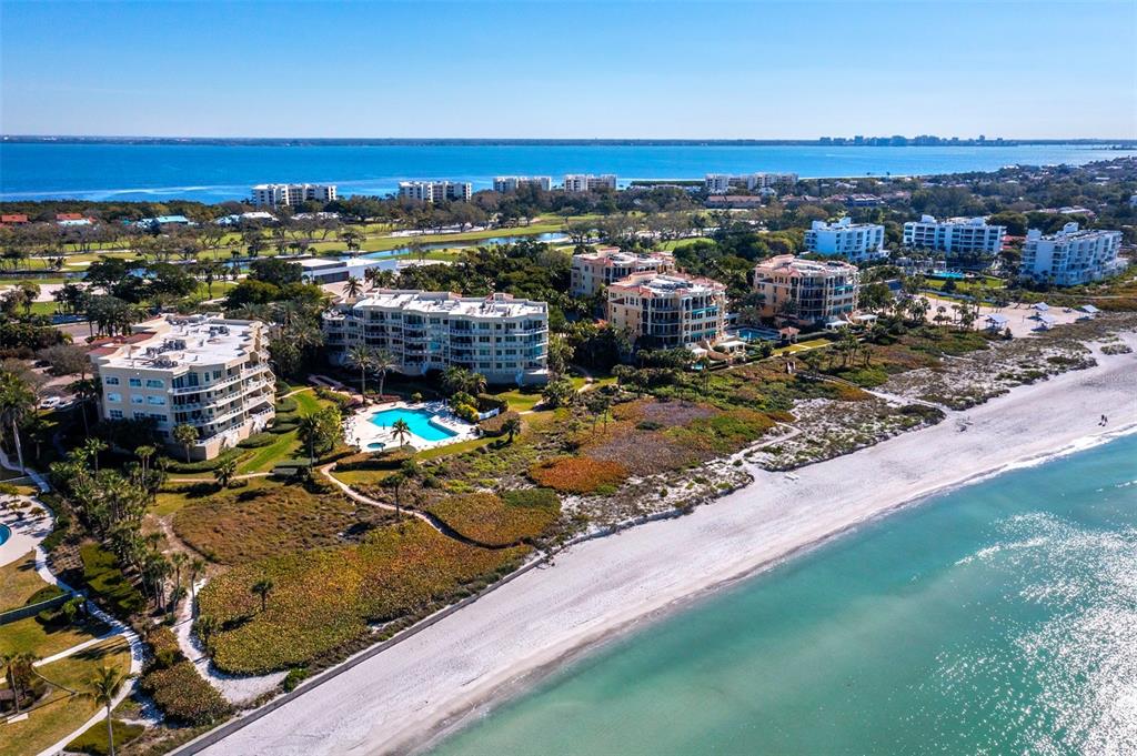 An aerial view of beachfront condominium buildings with swimming pools and surrounding coastal vegetation — 2185 GULF OF MEXICO DRIVE UNIT 212, LONGBOAT KEY, FL