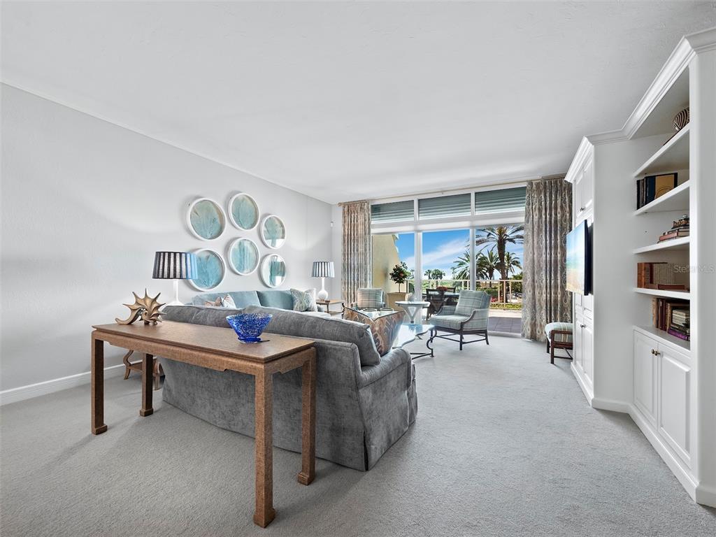 A living room features a gray sofa, a wooden console table, and built-in white shelving — 2185 GULF OF MEXICO DRIVE UNIT 212, LONGBOAT KEY, FL