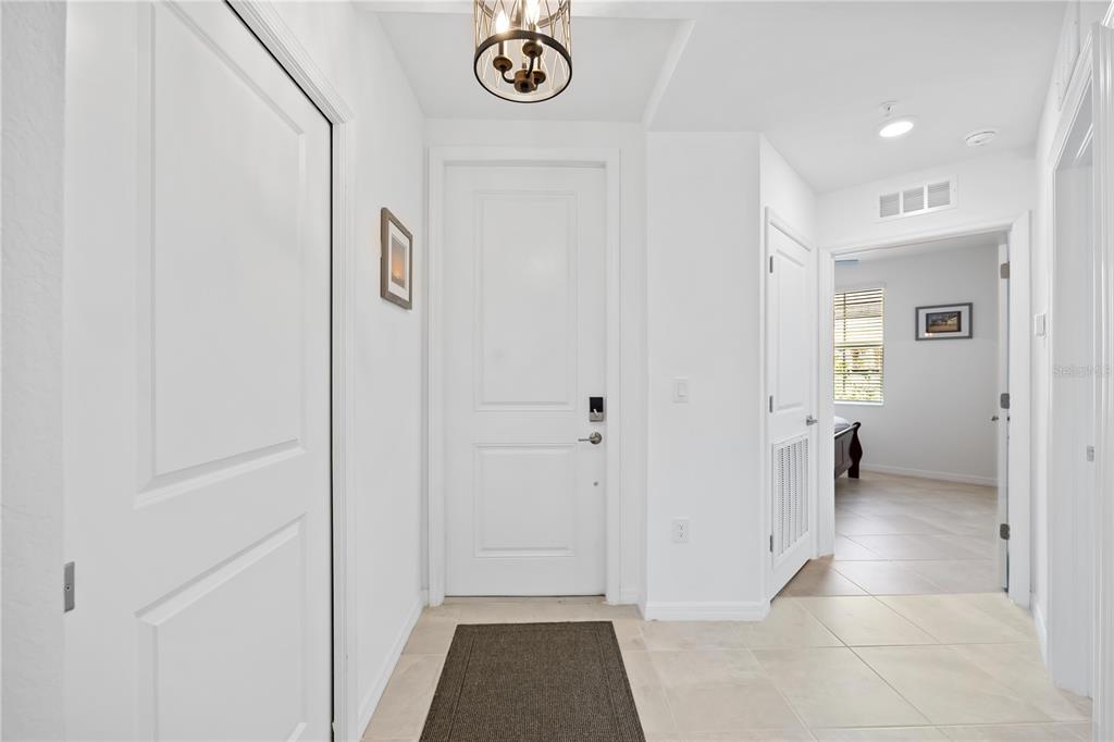 A bright entryway features white walls, tile flooring, a dark rug, and a central light fixture — 12140 WELLEN GOLF STREET UNIT 101, VENICE, FL