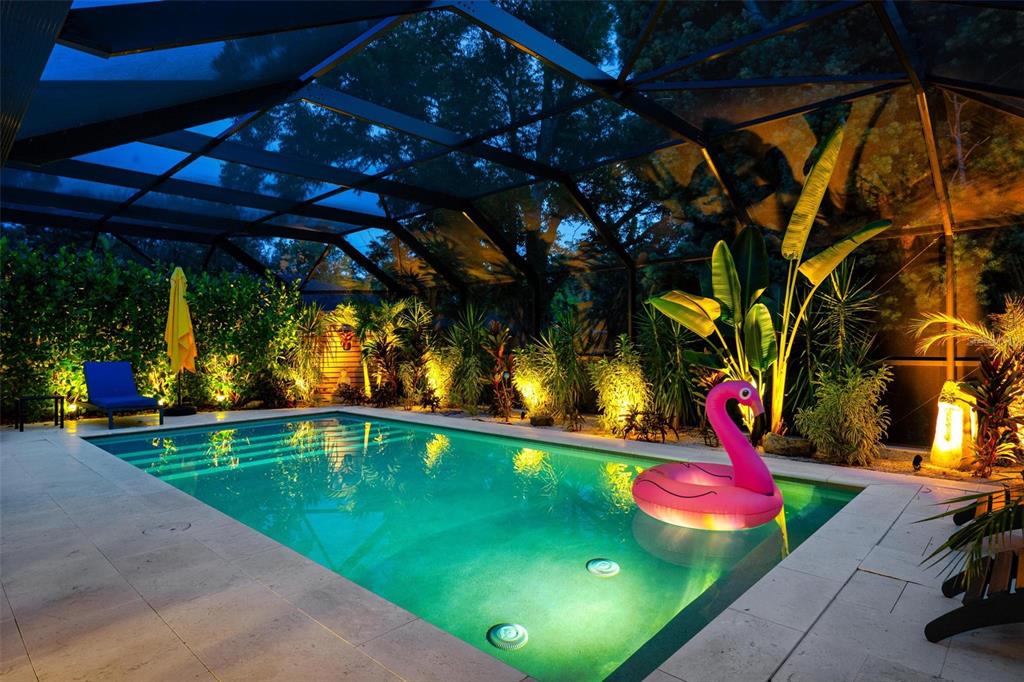 A swimming pool with a pink flamingo float inside a screened-in lanai at night — 403 51ST STREET NW, BRADENTON, FL
