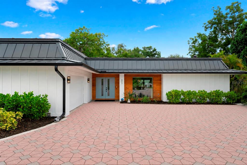 A single-story house with a white exterior, wood accent wall, and a dark metal roof — 403 51ST STREET NW, BRADENTON, FL