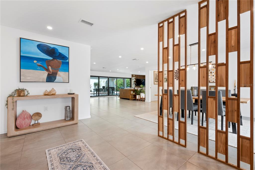 A modern entryway features a wooden console table, a large painting, and a decorative wood screen — 403 51ST STREET NW, BRADENTON, FL