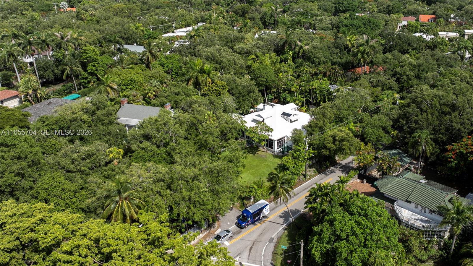 An aerial view shows a white house surrounded by dense trees near a paved road — 1701 S Bayshore Drive, Miami FL 33133, MIAMI, FL