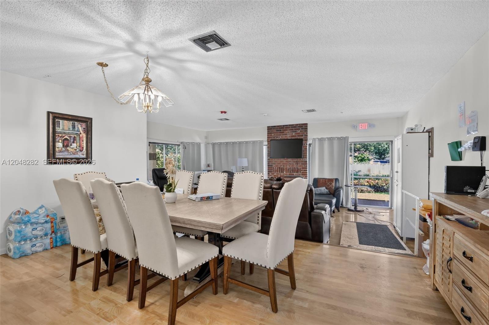 A dining area with a wooden table and upholstered chairs opens into a living room — 12104 Landing Way, Cooper City FL 33026, COOPER CITY, FL