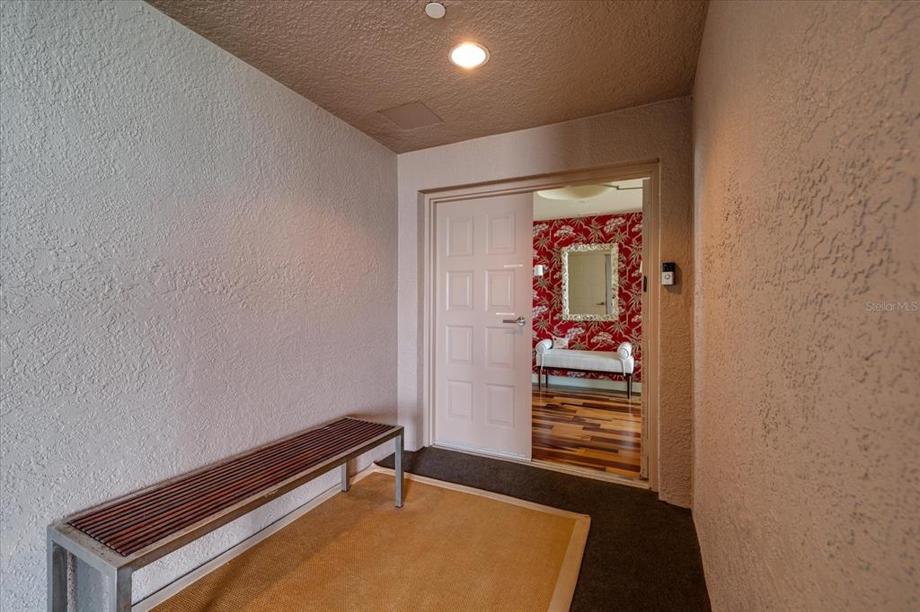 An entryway features a bench, a textured wall, and a doorway leading to a room — 1560 GULF BOULEVARD UNIT 1101, CLEARWATER BEACH, FL
