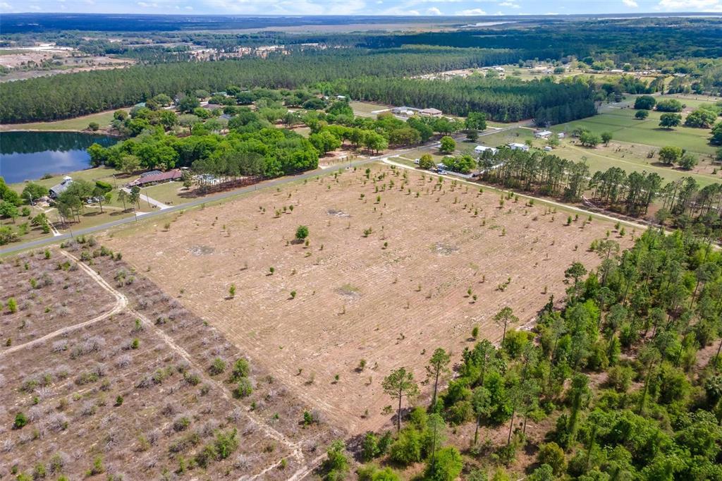 An aerial view shows a large, cleared rectangular plot of land surrounded by trees — SE 170TH AVENUE, WEIRSDALE, FL