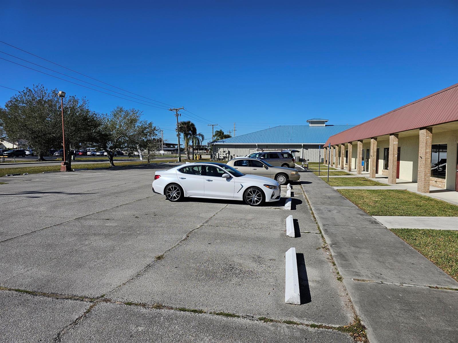 A white sedan is parked in a paved lot in front of a commercial building — 111 NE 19th Drive, Okeechobee FL 34972, OKEECHOBEE, FL
