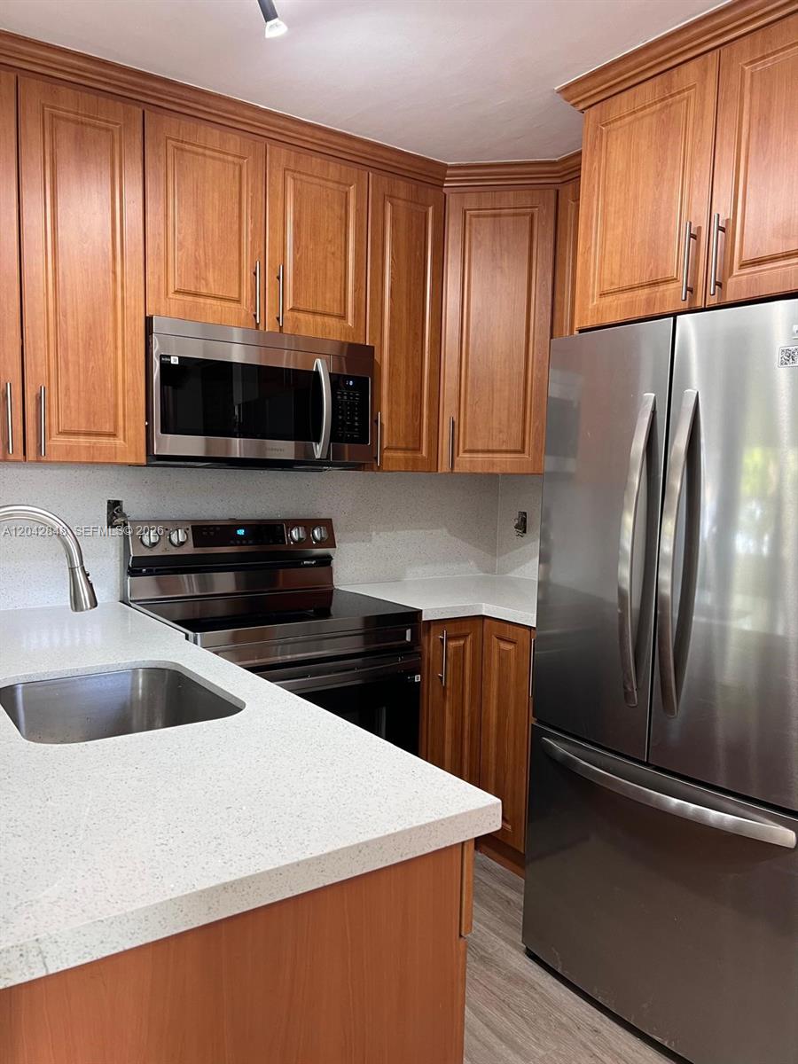 A kitchen features wood cabinets, stainless steel appliances, and white countertops — 6455 W 27th Ave # 44, Hialeah FL 33016, HIALEAH, FL