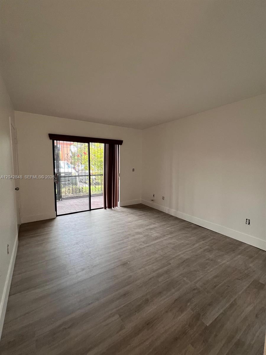 An empty room features light wood-look flooring, white walls, and a sliding glass door — 6455 W 27th Ave # 44, Hialeah FL 33016, HIALEAH, FL