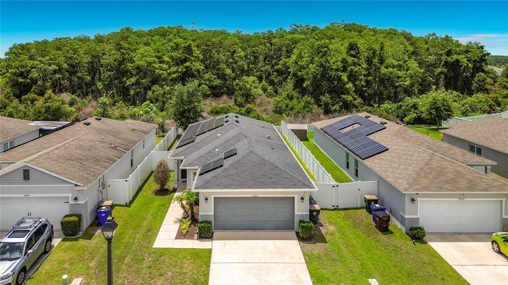 A single-story house with a gray garage, solar panels, and a concrete walkway — 3040 LAKES CREST AVENUE, ST CLOUD, FL