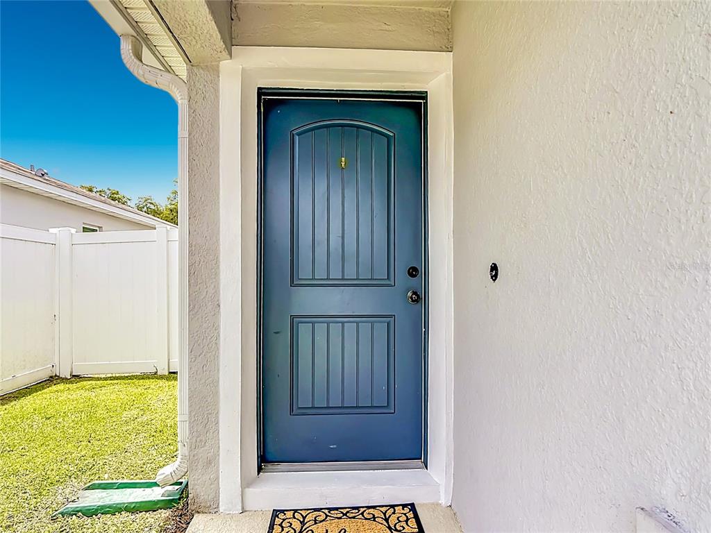 A blue front door with vertical panels is set into a white exterior wall — 3040 LAKES CREST AVENUE, ST CLOUD, FL