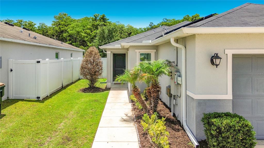 A concrete walkway leads to the front entrance of a house with a white fence — 3040 LAKES CREST AVENUE, ST CLOUD, FL