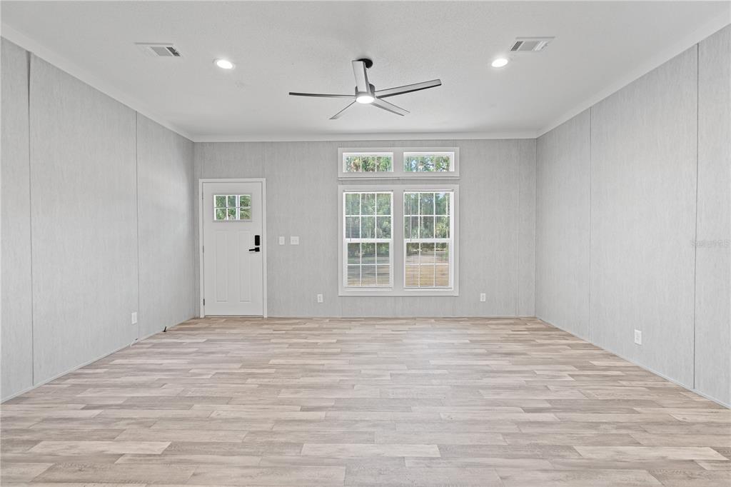 An empty room features light gray walls, wood-look flooring, a ceiling fan, and a door — 375 SAPP STREET, INGLIS, FL