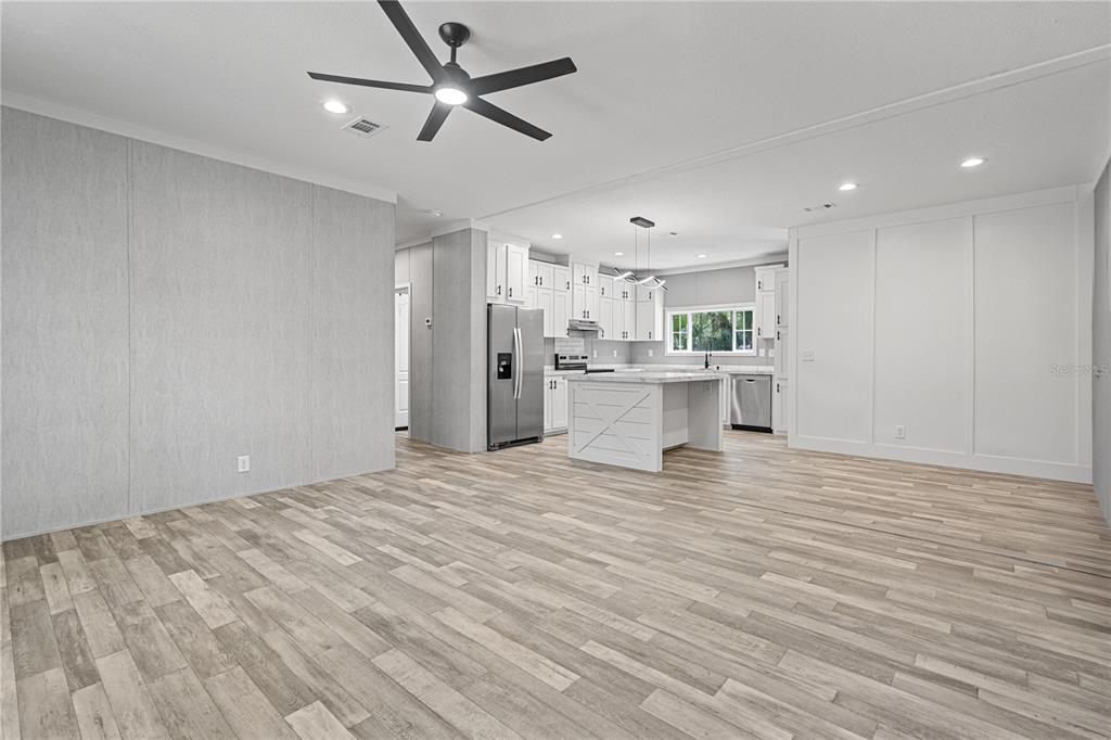 An open-concept kitchen and living area featuring light wood-look flooring and white cabinetry — 375 SAPP STREET, INGLIS, FL