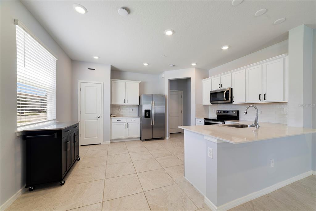 A kitchen features white cabinets, stainless steel appliances, a kitchen island, and light tile flooring — 2857 CLEVER LANE, WINTER PARK, FL