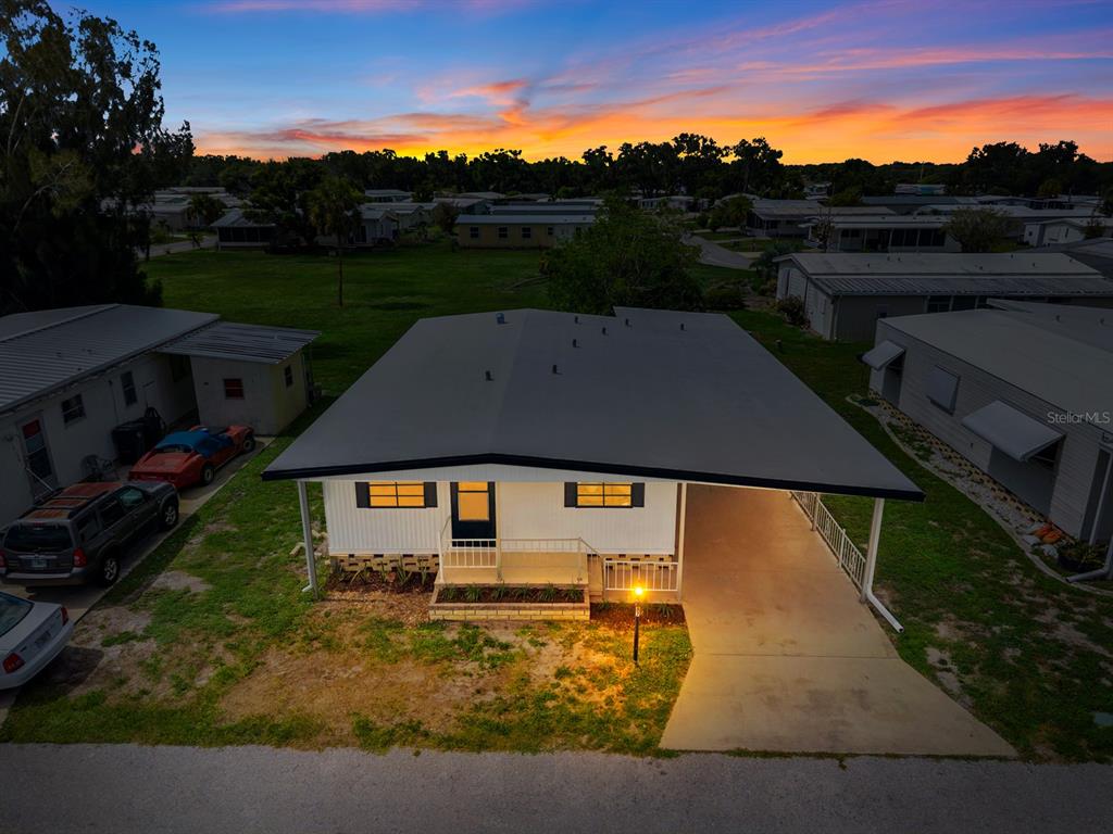An aerial view of a single-story home with a carport at sunset — 6710 36TH AVENUE E UNIT 87, PALMETTO, FL