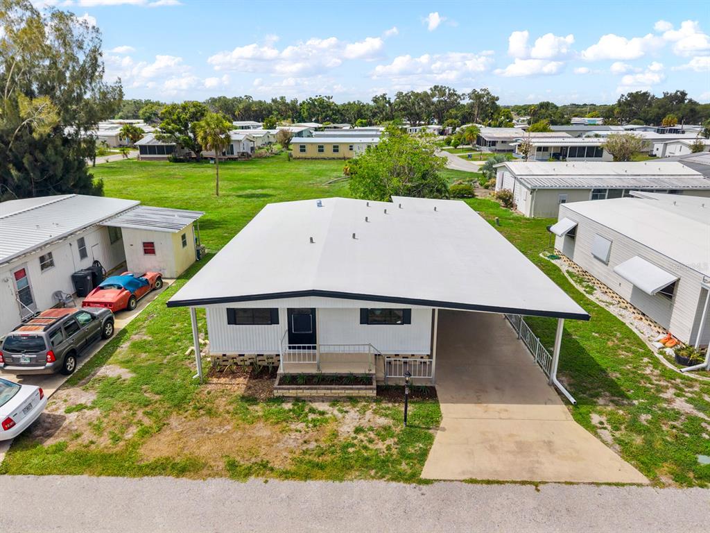 An aerial view of a white mobile home with a carport and adjacent vehicles — 6710 36TH AVENUE E UNIT 87, PALMETTO, FL