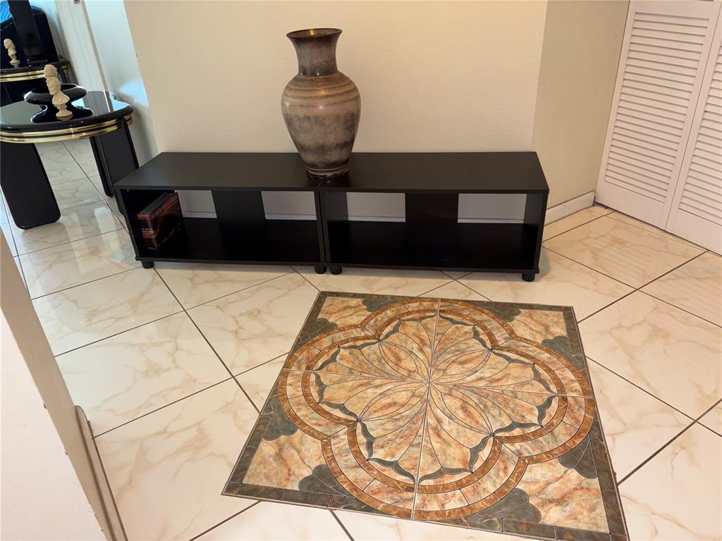 A black media console with a vase sits on a tiled floor with an inlay — 2333 FEATHER SOUND DRIVE UNIT C107, CLEARWATER, FL