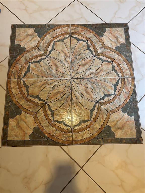 A decorative four-tile medallion with a floral pattern is centered on a light-colored tiled floor — 2333 FEATHER SOUND DRIVE UNIT C107, CLEARWATER, FL