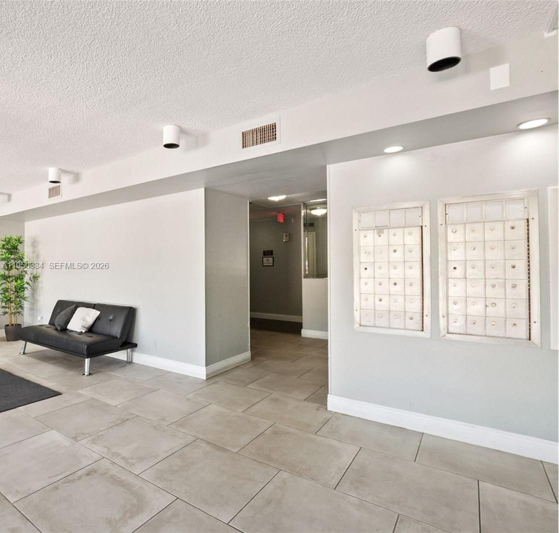 A lobby area features tiled floors, a black sofa, and wall-mounted mailboxes — 2771 Taft St # 411, Hollywood FL 33020, HOLLYWOOD, FL