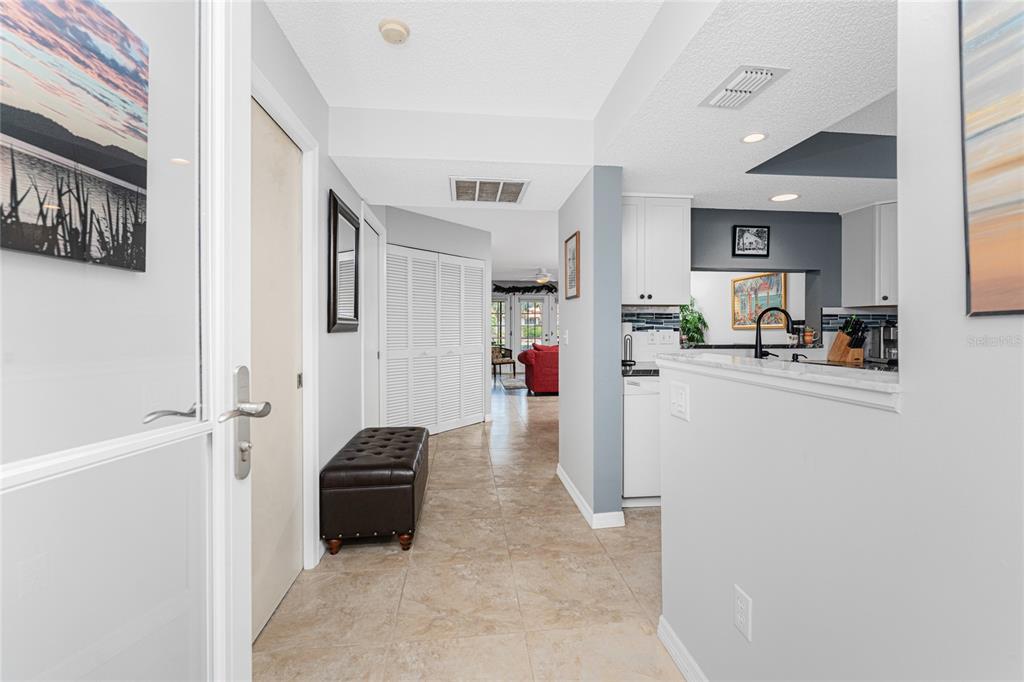A tiled entryway leads past a kitchen with white cabinets toward a living area — 511 PINE HOLLOW CIRCLE UNIT 511, ENGLEWOOD, FL