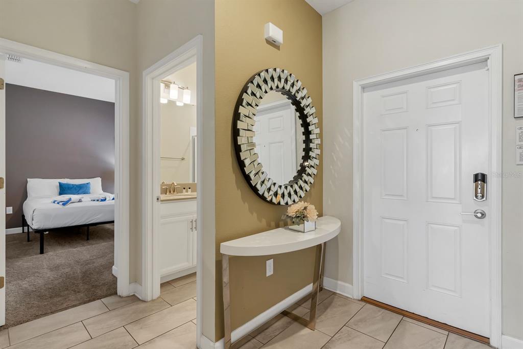 An entryway features a white console table, a decorative round mirror, and a tiled floor — 4914 WINDERMERE AVENUE, KISSIMMEE, FL