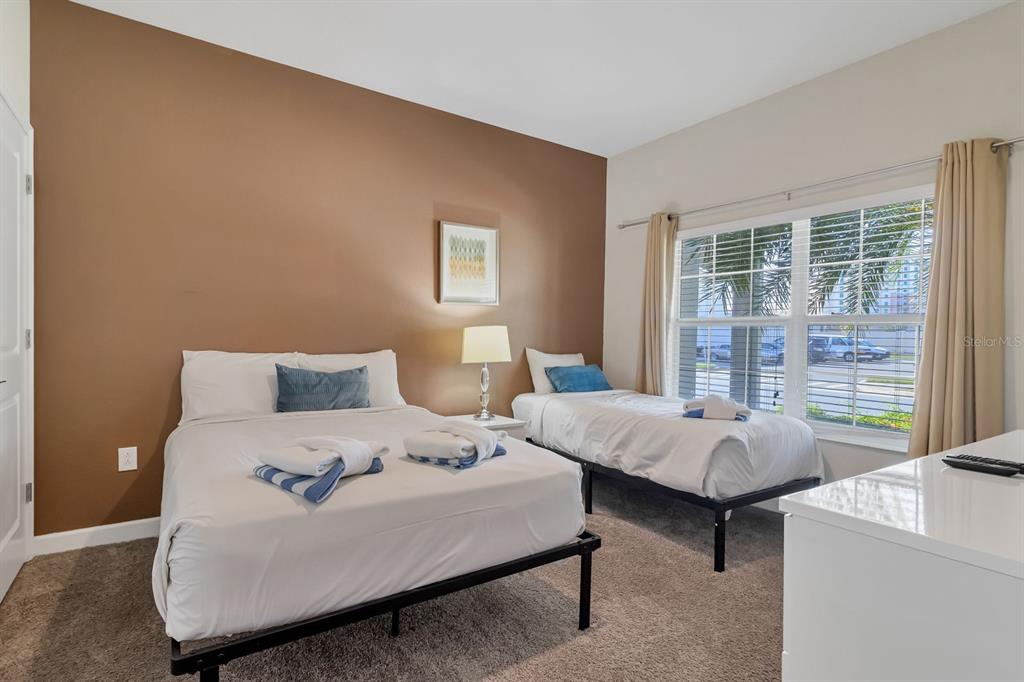 A bedroom features a queen bed, a twin bed, and a large window with curtains — 4914 WINDERMERE AVENUE, KISSIMMEE, FL