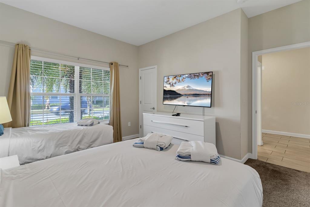 A bedroom features a bed, a twin bed, a white dresser, and a wall-mounted television — 4914 WINDERMERE AVENUE, KISSIMMEE, FL