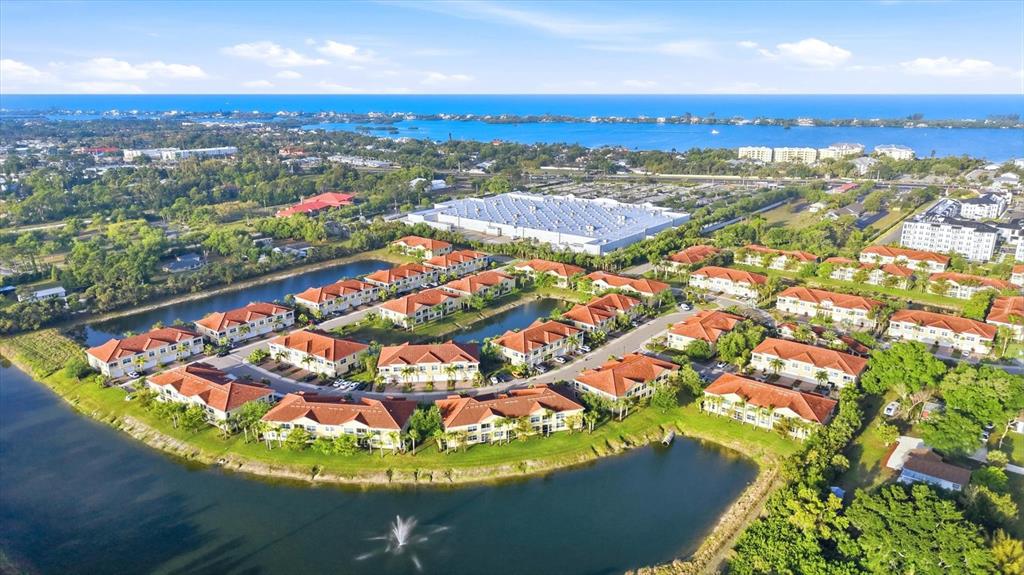 An aerial view shows a residential complex with multiple buildings surrounding a central pond — 173 NAVIGATION CIRCLE UNIT 107, OSPREY, FL