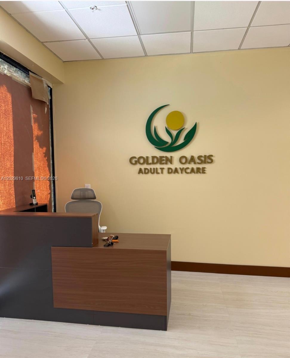 A reception area features a wooden desk, an office chair, and a wall sign — MIAMI, FL