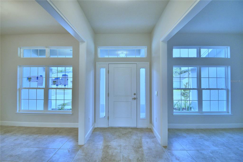 An entryway features a white front door with sidelights, tile flooring, and large windows — 4429 JUNEBERRY DRIVE, AUBURNDALE, FL