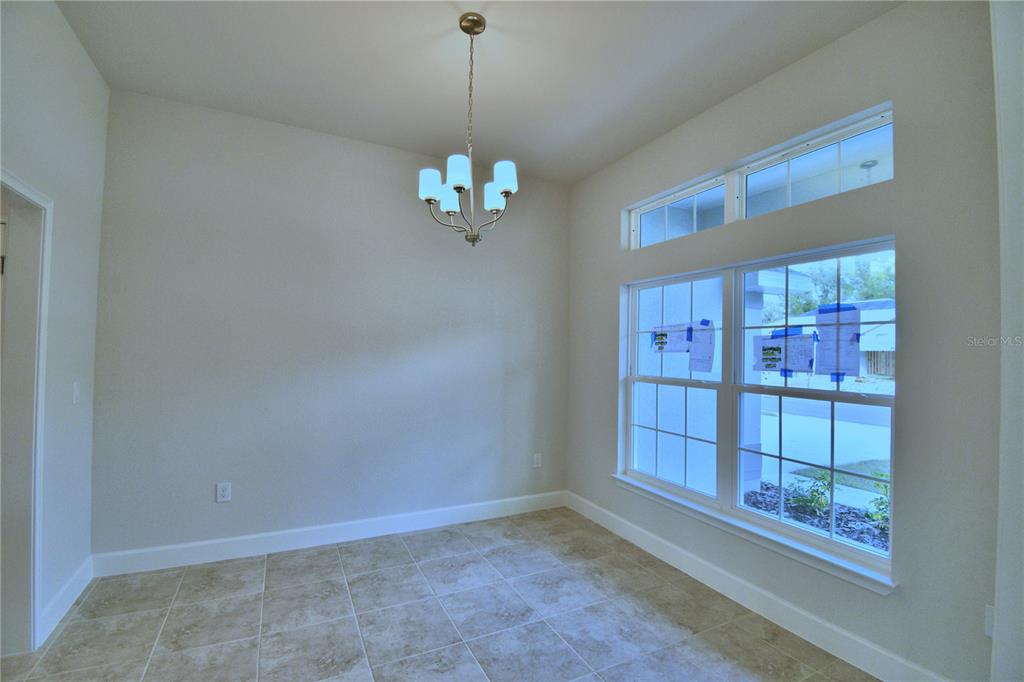 A dining area with tile flooring, a chandelier, and large windows with paper coverings — 4429 JUNEBERRY DRIVE, AUBURNDALE, FL