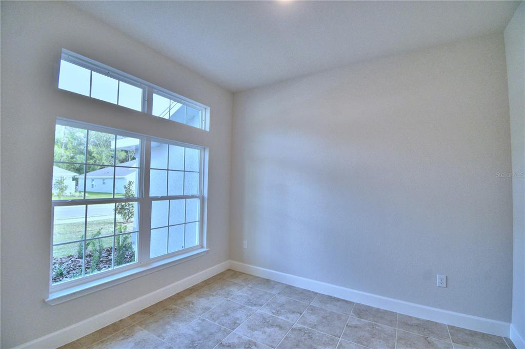 An empty room with light-colored walls, tile flooring, and large windows with a transom — 4429 JUNEBERRY DRIVE, AUBURNDALE, FL