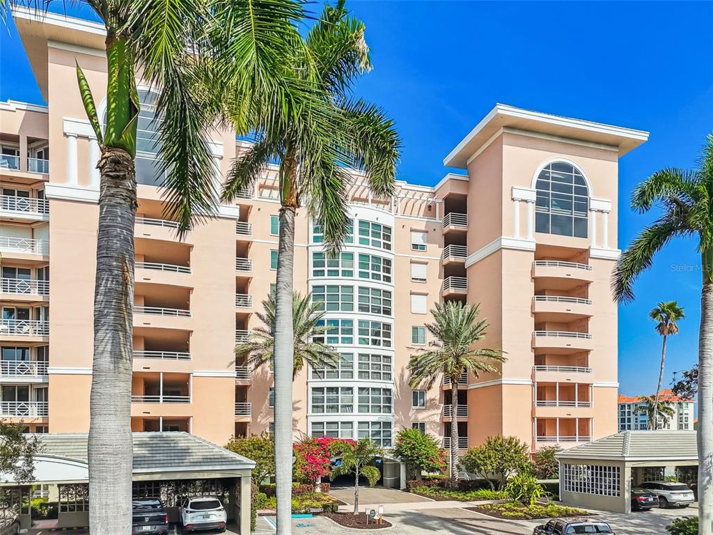 A multi-story peach-colored apartment building features balconies, arched windows, and palm trees in front — 4991 BACOPA LANE S UNIT 502, ST PETERSBURG, FL