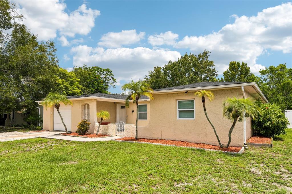 A single-story beige stucco house with a garage, palm trees, and a grassy front yard — 7303 HEATH DRIVE, PORT RICHEY, FL